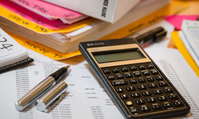 calculadora, pasta com impostos e documentos estão em cima da mesa